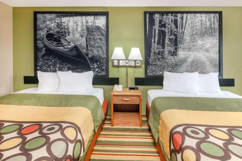 a hotel room with two beds and a table at Super 8 by Wyndham Grayling in Grayling