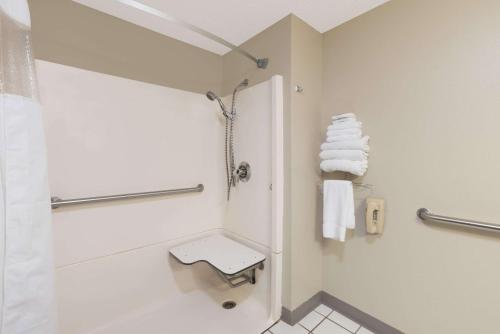a bathroom with a shower and a toilet and towels at Super 8 by Wyndham Pierre SD in Pierre