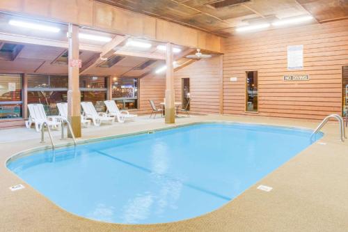 a large blue pool in a room with chairs and tables at Super 8 by Wyndham Mitchell in Mitchell