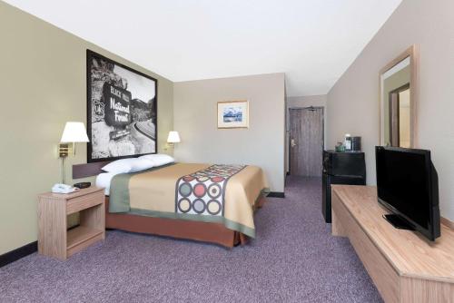a hotel room with a bed and a flat screen tv at Super 8 by Wyndham Winner SD in Winner