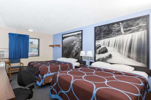 a hotel room with two beds and a wall mural at Super 8 by Wyndham Manhattan KS in Manhattan