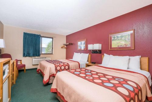 two beds in a hotel room with red walls at Super 8 by Wyndham Baxter/Brainerd Area in Baxter