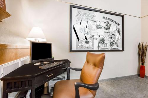 a desk with a computer and a chair in a room at Super 8 by Wyndham Manhattan KS in Manhattan
