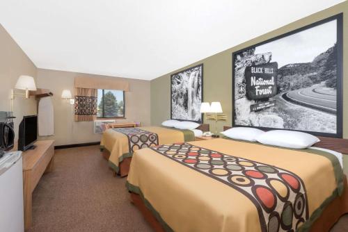 a hotel room with two beds and a large screen at Super 8 by Wyndham Winner SD in Winner