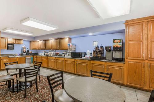 a kitchen with wooden cabinets and tables and chairs at Super 8 by Wyndham Manhattan KS in Manhattan
