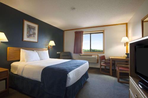 a hotel room with a bed and a desk and a television at Super 8 by Wyndham Eveleth in Eveleth