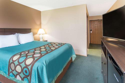 a hotel room with a bed and a flat screen tv at Super 8 by Wyndham Austin MN in Austin