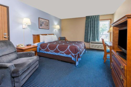 a hotel room with a bed and a couch and a television at Super 8 by Wyndham O'Fallon MO/St. Louis Area in O'Fallon