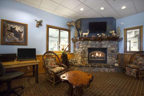 a living room with a fireplace and a desk and chairs at Super 8 by Wyndham Eveleth in Eveleth