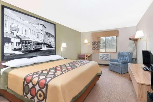 a hotel room with a large bed and a chair at Super 8 by Wyndham Winner SD in Winner