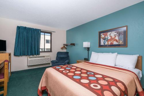 a hotel room with a bed and a chair at Super 8 by Wyndham Baxter/Brainerd Area in Baxter