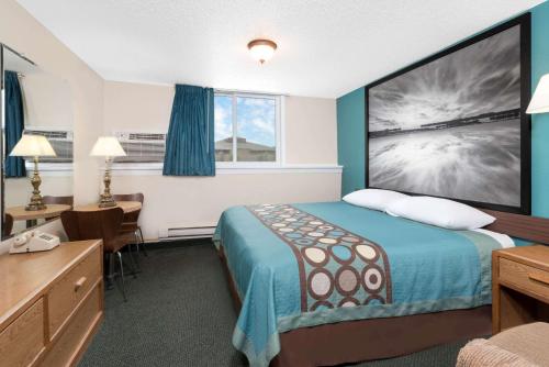 a hotel room with a bed and a desk at Super 8 by Wyndham Huron in Huron
