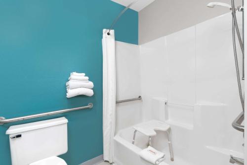 a bathroom with a white toilet and a blue wall at Super 8 by Wyndham Huron in Huron