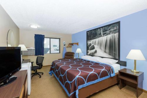 a hotel room with a bed and a flat screen tv at Super 8 by Wyndham Manhattan KS in Manhattan