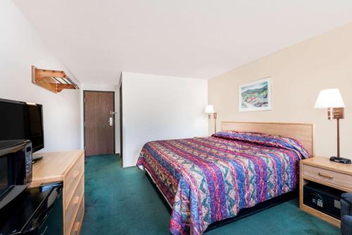a hotel room with a bed and a flat screen tv at Super 8 by Wyndham Belle Fourche SD in Belle Fourche