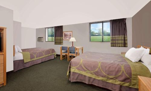 a hotel room with two beds and a desk at Super 8 by Wyndham Spearfish in Spearfish