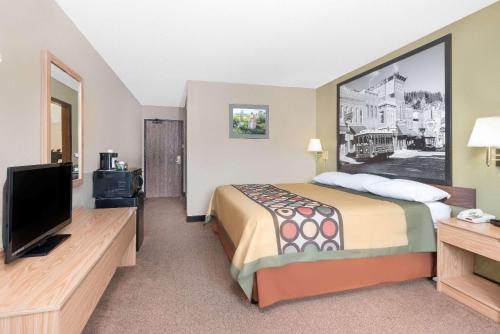 a hotel room with a bed and a flat screen tv at Super 8 by Wyndham Winner SD in Winner