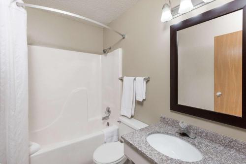 a bathroom with a sink and a toilet and a mirror at Super 8 by Wyndham Manhattan KS in Manhattan