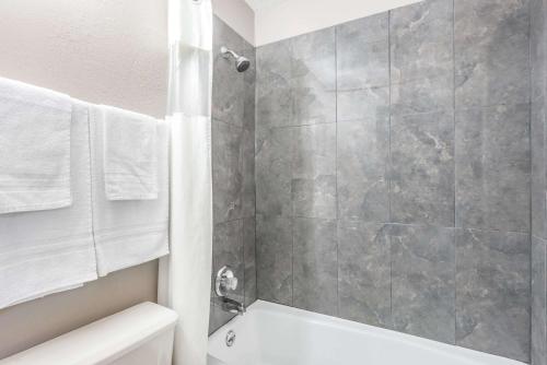 a bathroom with a shower and a white tub at Super 8 by Wyndham O'Fallon MO/St. Louis Area in O'Fallon