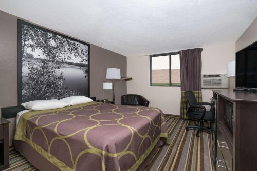 a hotel room with a bed and a flat screen tv at Super 8 by Wyndham Willmar in Willmar