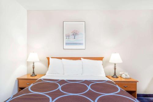 a bed in a hotel room with two lamps at Super 8 by Wyndham Montgomery Maybrook in Montgomery