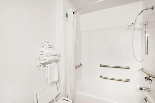a white bathroom with a shower and a toilet at Super 8 by Wyndham Newburgh/West Point Stewart Intl Airport in Newburgh