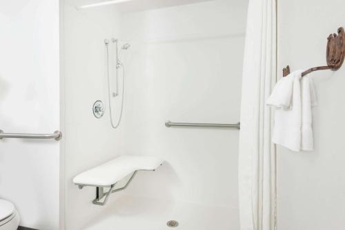 a white bathroom with a shower and a toilet at Super 8 by Wyndham Powell in Powell