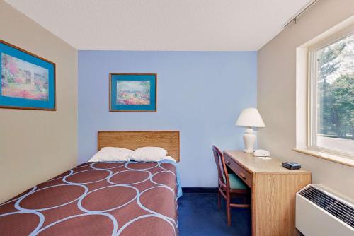 a room with a bed and a desk and a window at Super 8 by Wyndham Newburgh/West Point Stewart Intl Airport in Newburgh
