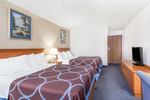 a hotel room with a large bed and a television at Super 8 by Wyndham Montgomery Maybrook in Montgomery