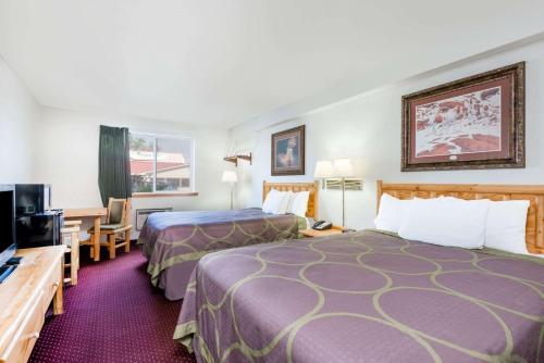 a hotel room with two beds and a flat screen tv at Super 8 by Wyndham Powell in Powell