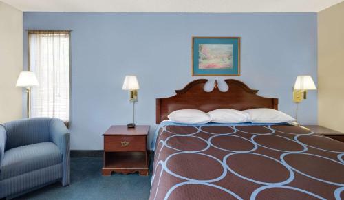a hotel room with a bed and a chair at Super 8 by Wyndham Newburgh/West Point Stewart Intl Airport in Newburgh