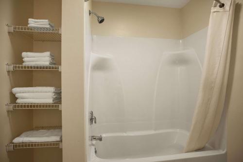 a bathroom with a tub and a shower with towels at Super 8 by Wyndham Mifflinville Near Bloomsburg in Mifflinville