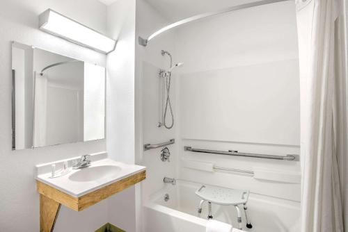 y baño blanco con lavabo y bañera. en Super 8 by Wyndham Ticonderoga, en Ticonderoga