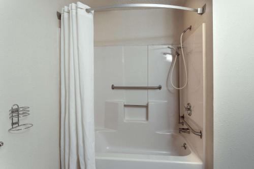 Super 8 by Wyndham Hartford WI في Hartford: حمام مع دش وحوض استحمام أبيض