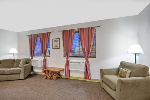 a living room with two chairs and a table and two windows at Super 8 by Wyndham Ticonderoga in Ticonderoga