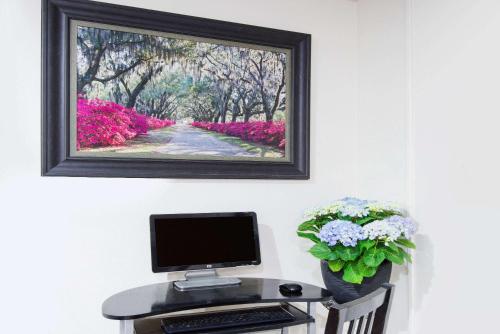 a computer on a desk with a picture on the wall at Super 8 by Wyndham Pittsburgh PA Airport-University Area in Moon Township