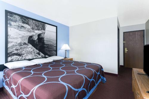 a hotel room with a bed with a large picture on the wall at Super 8 by Wyndham Wisconsin Dells in Wisconsin Dells