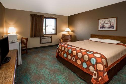 a hotel room with a bed and a television at Super 8 by Wyndham Hartford WI in Hartford