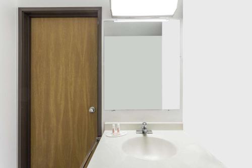 a bathroom with a sink and a wooden door at Super 8 by Wyndham Logan in Logan