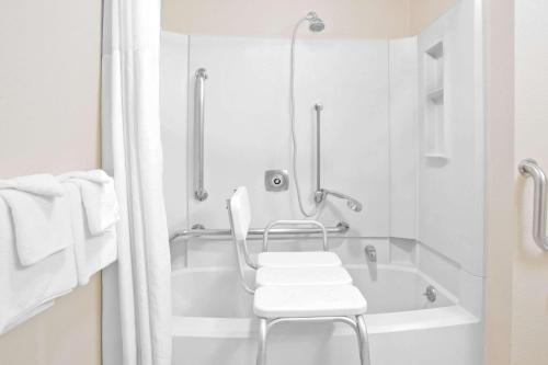 a white bathroom with a chair and a bath tub at Super 8 by Wyndham Havre in Havre