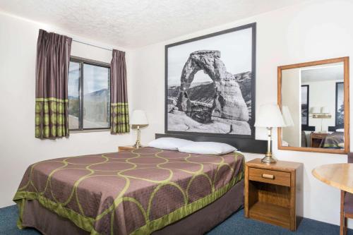 a hotel room with a bed and two windows at Super 8 by Wyndham Logan in Logan