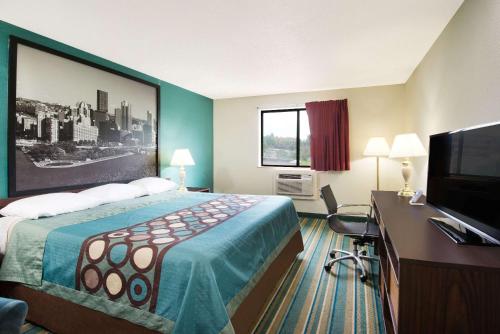 a hotel room with a bed and a desk with a television at Super 8 by Wyndham Pittsburgh PA Airport-University Area in Moon Township