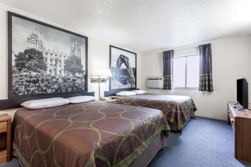 a hotel room with two beds and a large picture on the wall at Super 8 by Wyndham Logan in Logan