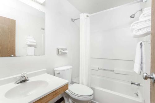 a white bathroom with a toilet and a sink at Super 8 by Wyndham Sidney NY in Sidney
