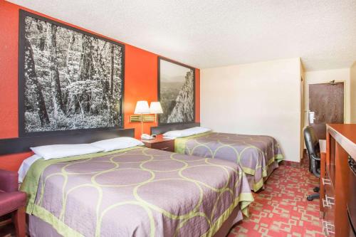 two beds in a hotel room with orange walls at Super 8 by Wyndham Harrisonburg in Harrisonburg