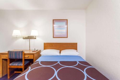 a small room with a bed and a desk and a table and chair at Super 8 by Wyndham Sidney NY in Sidney