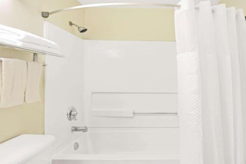 a bathroom with a shower with a white shower curtain at Super 8 by Wyndham Newport News/Jefferson Ave. in Newport News