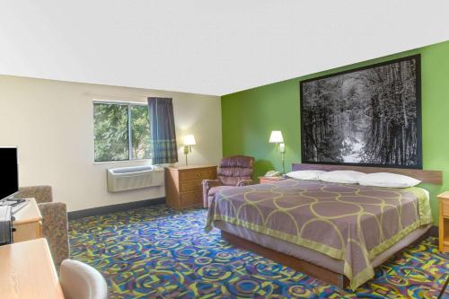 a hotel room with a bed and a chair at Super 8 by Wyndham Radford VA in Radford