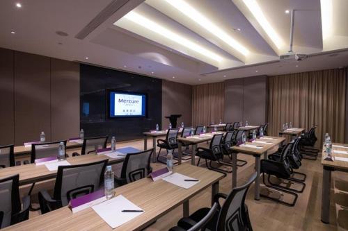 a conference room with tables and chairs and a projection screen at Mercure Shanghai Jiuting in Shang-hai
