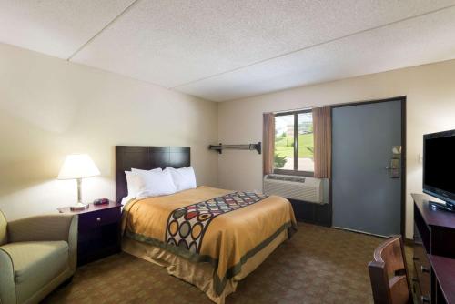 ホワイト・リバー・ジャンクションにあるSuper 8 by Wyndham White River Junctionのベッドとテレビが備わるホテルルームです。